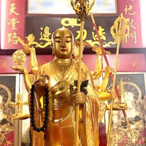 A statue of buddha with many hands holding the staff.