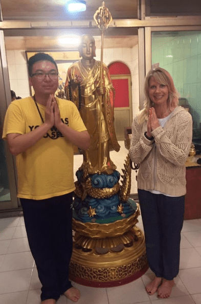 A man and woman standing next to a statue.